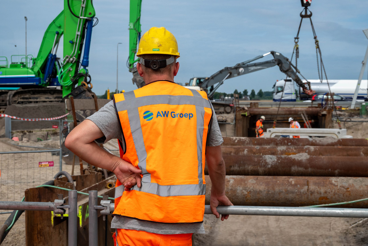 Man in oranje hesje kijkt naar constructie.